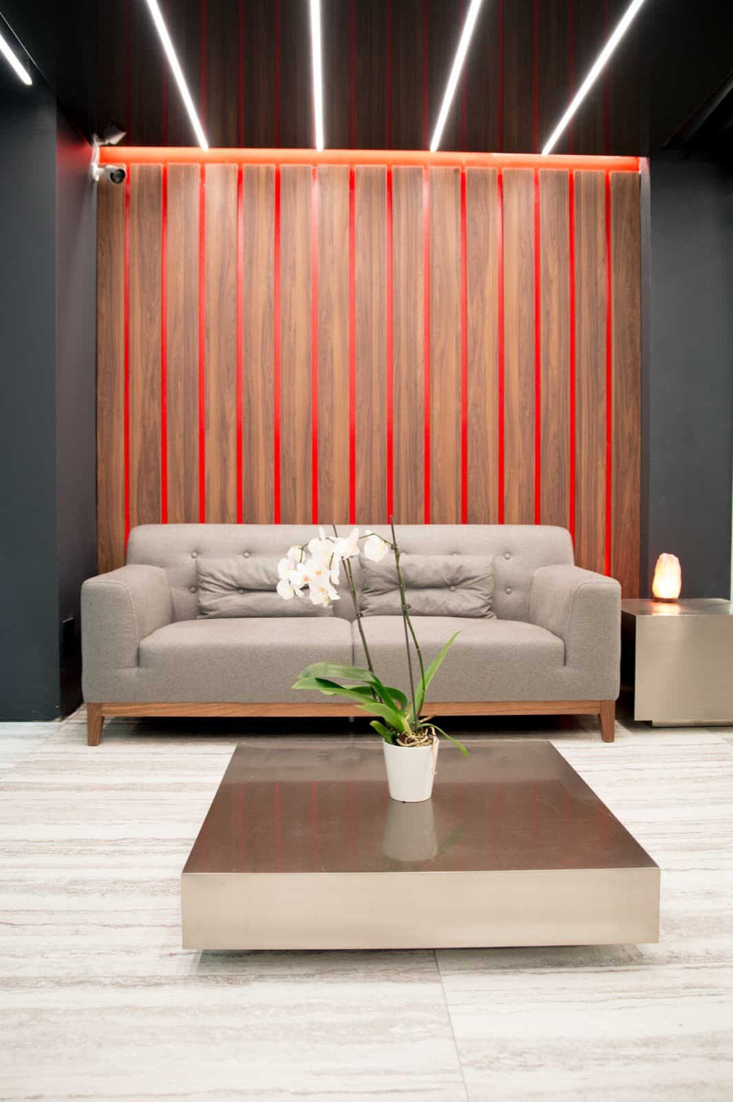 The warm, backlit reception lounge with a designer sofa and fresh orchid at the GoGo studio