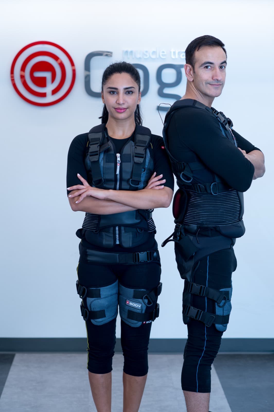 A man and a woman in EMS suits stand back-to-back in front of the GoGo logo